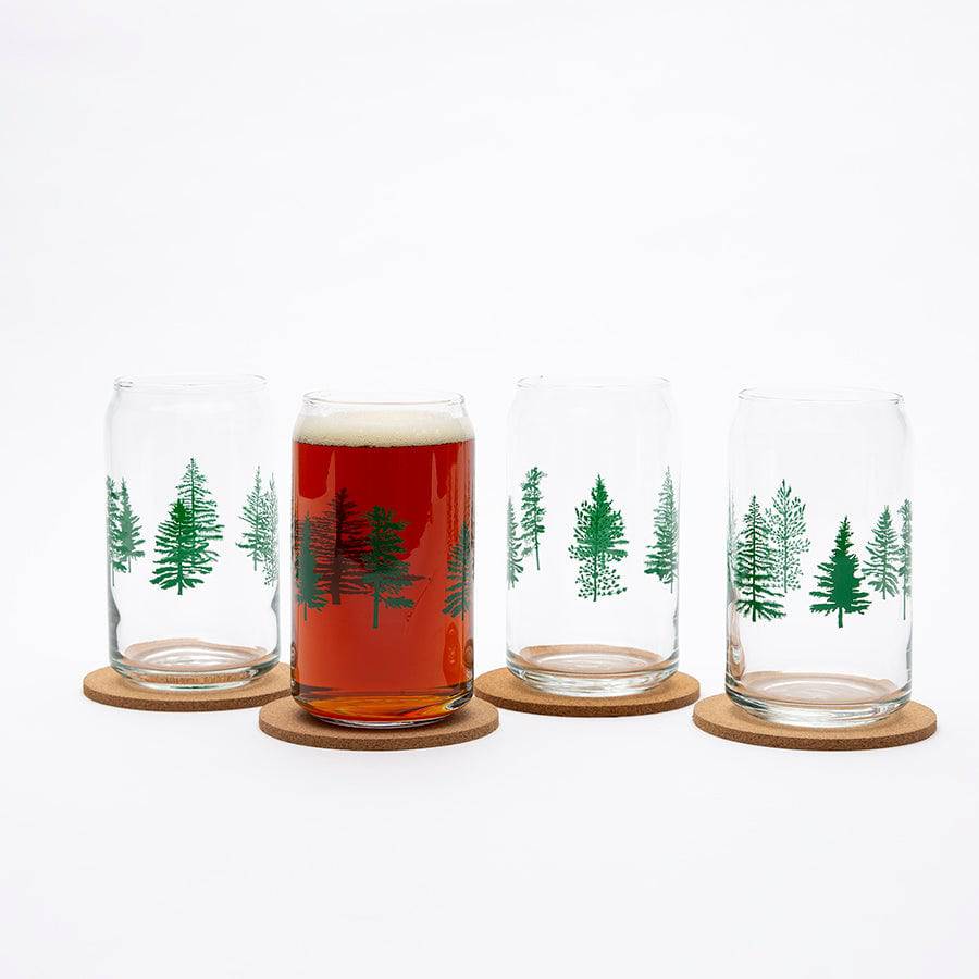 Set of four clear can-shaped beer glasses with green tree designs on cork coasters