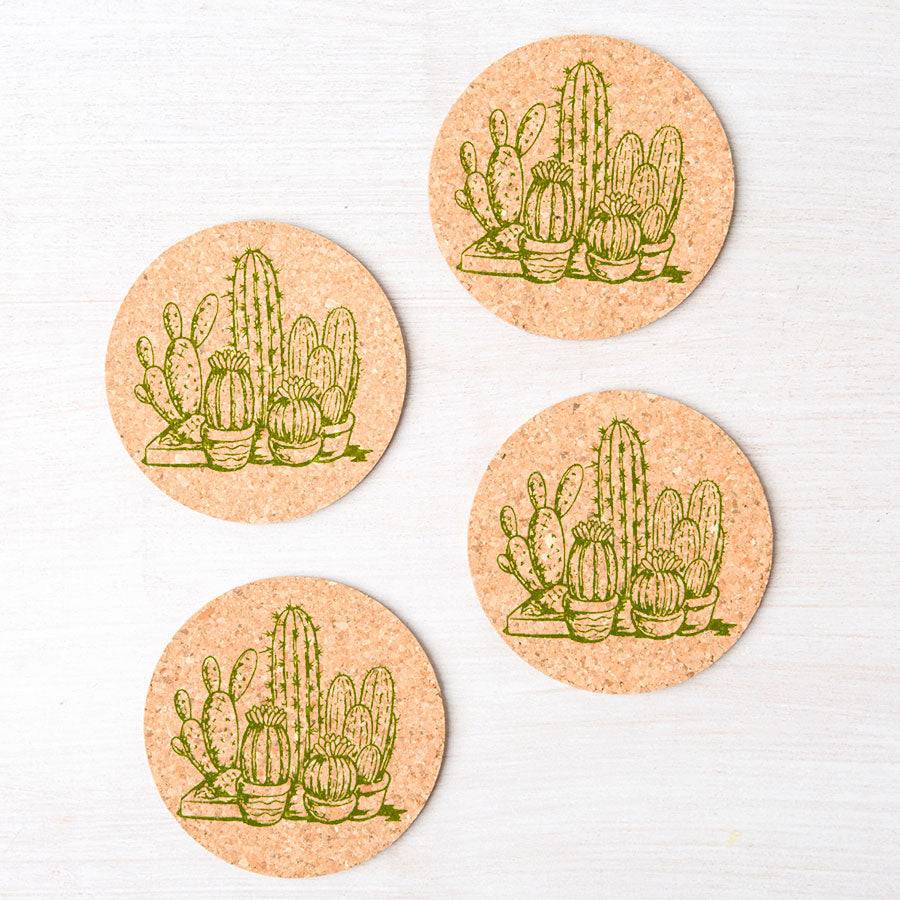 Set of four round cork coasters with green cactus illustrations on a white surface