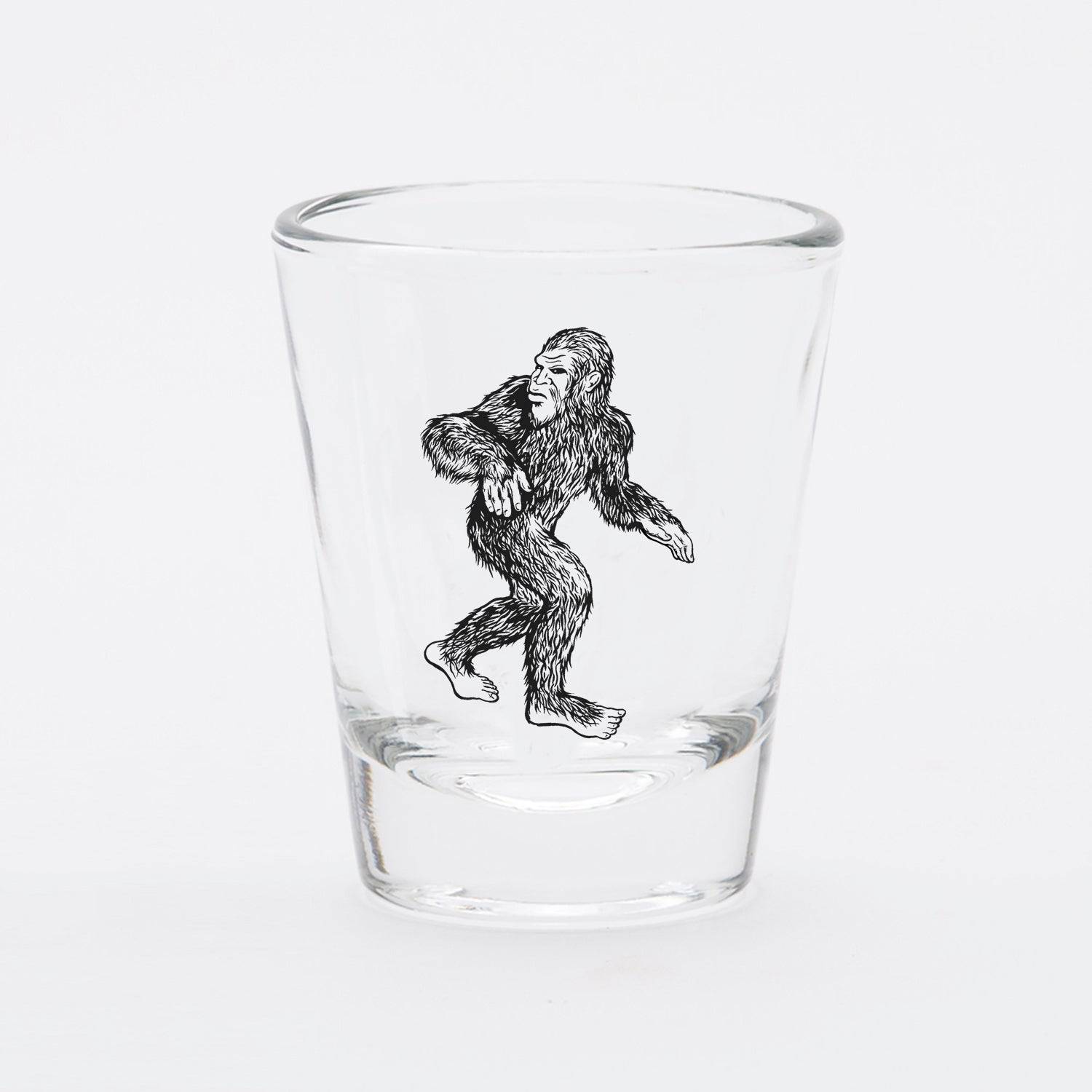 Clear shot glass with black Sasquatch illustration, novelty barware for home or gifts